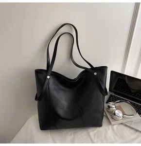 Detail of minimalist black tote bag with silver rivets and sleek texture for work