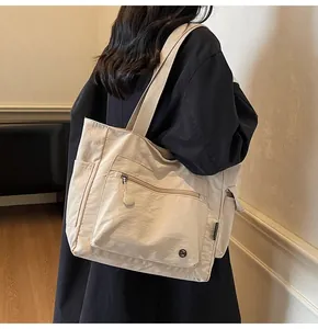 Detailed view of cream-white tote bag featuring multi-pocket design and wide fabric straps