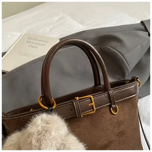 Gros plan du sac seau marron mat vintage avec détails en cuir et pendentif en peluche
