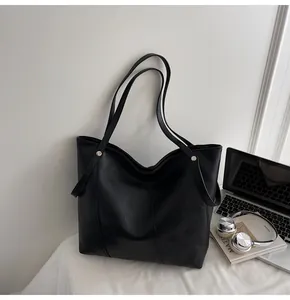 Detail view of large black tote bag featuring premium texture and silver metal rivets