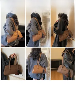 Brown textured leather tote bag with shoulder straps and small charm accessory