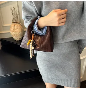 Detail of dark brown woven handbag with wooden beads and blue striped lining details