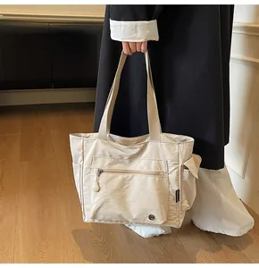 Detailed view of beige nylon tote bag with functional pockets and brand label