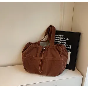 Détail du sac fourre-tout en velours côtelé marron avec cordon et deux poches avant