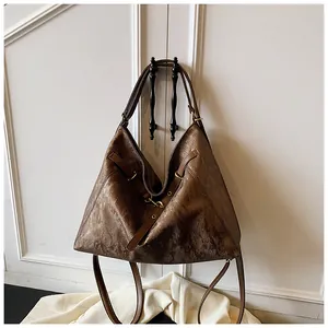 Detailed view of the vintage brown leather texture and bronze buckle on the large tote bag