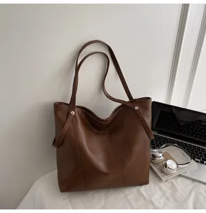 Detailed view of dark brown tote bag with silver rivets on textured faux leather