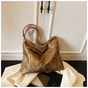 Detail of metallic gold tote bag featuring wrinkled texture and adjustable buckle straps