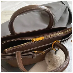 Détail du cabas marron foncé avec fermeture éclair dorée et porte-clés lapin en peluche