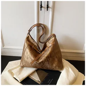 Detail of metallic bronze tote bag featuring brushed texture and gold hardware accents