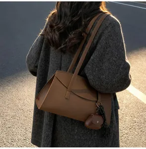 Detailed view of a brown leather shoulder bag with matching coin purse on a tweed coat