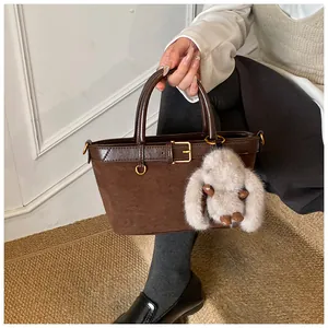 Détail d'un sac seau rétro marron foncé en daim avec bordure en cuir et porte-clés
