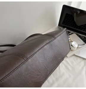 Macro shot of dark brown PU leather tote bag with reinforced stitching and soft texture