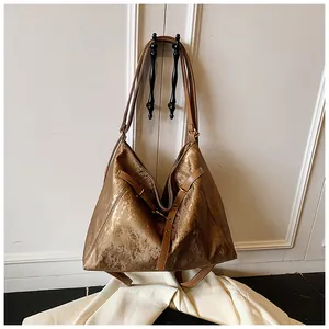 Detail of metallic gold hobo tote featuring textured synthetic leather and metal rings