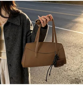 Detail of brown leather tote bag with mini purse pendant and woven charm decoration