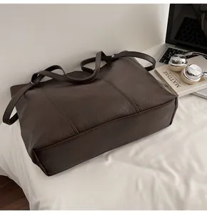 Detail of a large dark brown faux leather tote bag with books and laptop for work