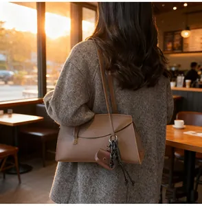 Close-up of caramel leather shoulder bag with decorative chain in a warm cafe setting
