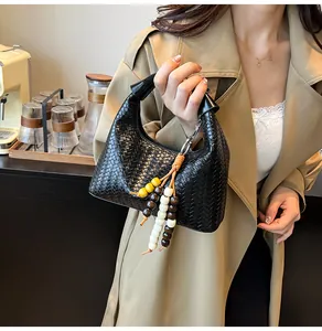 Close-up of black woven hobo handbag featuring a decorative multi-color wooden bead tassel