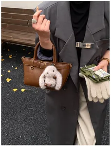 Détail d'un cabas en cuir marron avec boucle de ceinture et porte-clés lapin pelucheux