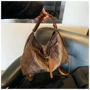 Detailed close-up of dark brown tote bag with vintage texture and gold hardware details
