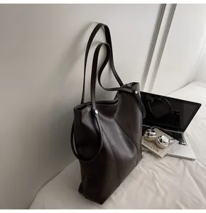 Detail of dark brown tote bag with V-shaped stitching and matte leather texture