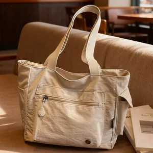 Minimalist beige nylon tote bag with multi-pocket design on a sofa for daily commute