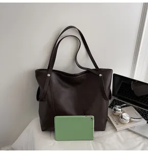 Detailed view of large dark brown tote bag interior fitting a green tablet and daily items