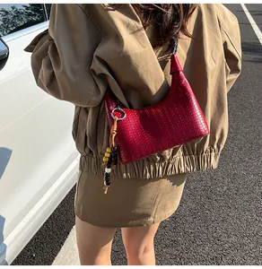 Detail of red woven leather hobo bag featuring silver ring and colorful bead tassel