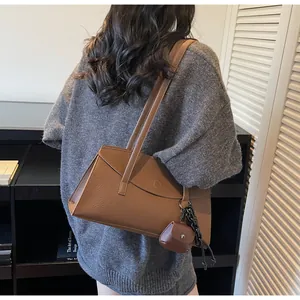 Detail of brown litchi pattern leather tote bag with mini pouch and black chain strap