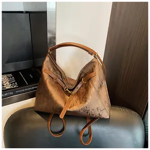 Detail showing the bronze metallic texture and decorative leather strap of the tote bag