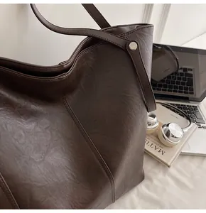 Detailed view of dark brown textured tote bag with fine stitching and laptop background