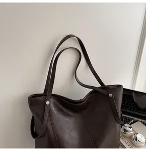 Detail view of dark coffee tote bag with leather texture in a modern office desk setting