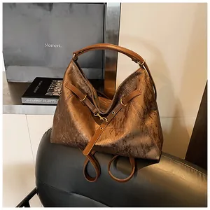 Detail of bronze silk tote bag texture and leather handle on a black leather chair