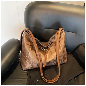 Detail of dark brown embossed leather tote with metallic sheen and slim shoulder straps
