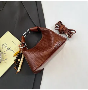 Detailed macro of a brown woven handbag with silver buckle and decorative beaded charm