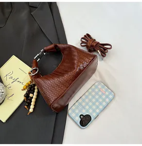 Close-up of woven dark brown hobo bag with vintage beaded tassel and slim strap