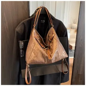Detail of a brown metallic tote bag with vintage texture and golden metal hook on strap