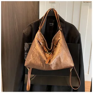 Close-up of brown textured tote bag with golden metallic hardware and slim shoulder strap