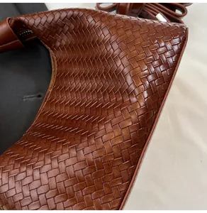 Close-up of brown leather woven handbag detailing the intricate crisscross braid pattern