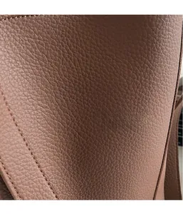 Detailed close-up of brown pebbled leather texture with precise double stitching on bucket bag