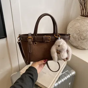 Sac seau marron mat rétro avec breloque lapin en peluche sur fond de bagage vintage
