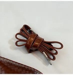 Close-up of brown woven texture and glossy leather strap with silver metal buckle