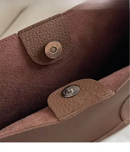 Macro view of coffee brown litchi leather detail and magnetic metal snap closure