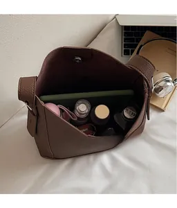 Macro view of spacious brown pebbled leather bucket bag interior showing daily essentials