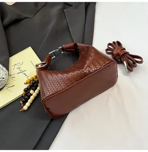Detailed close-up of dark brown woven texture handbag with wooden bead pendant charm