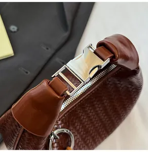Close-up of dark brown woven leather texture with silver metal buckle and zipper