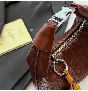 Detail of dark brown woven leather handbag with silver clasp and yellow tassel charm