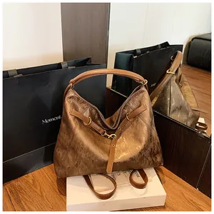 Detail of metallic bronze leather tote bag with vintage buckle and curved handle