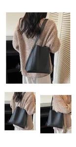 Detail view of black lychee grain leather bucket bag with fine stitching and slim strap