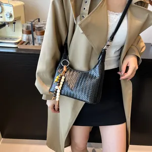 Chic black woven texture hobo bag with colorful beads detail in a modern cafe setting