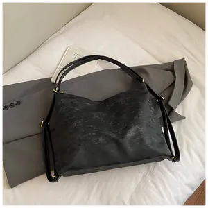 Detail of black marble textured tote bag with golden metal hardware and twin straps